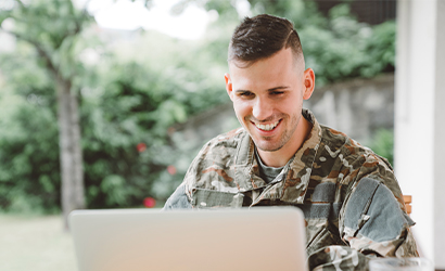 Military personnel smiling while at their laptop